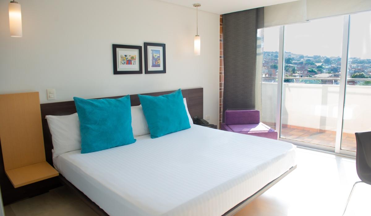 Habitación con vista al balcón y decoración vibrante en Hotel Casablanca Cúcuta. Habitación luminosa con cama grande, balcón y decoración colorida en Hotel Casablanca Cúcuta.