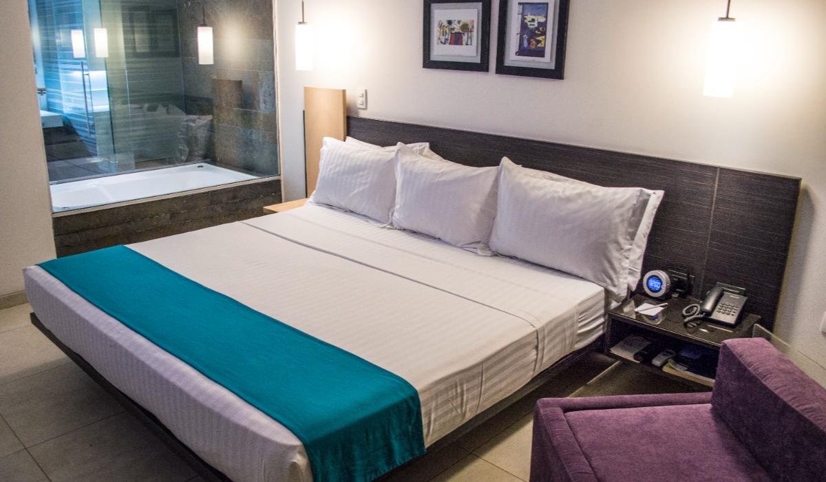 Habitación amplia con cama king y acentos en azul en Hotel Casablanca Cúcuta. Habitación con cama king, detalles en azul y cuadros decorativos en Hotel Casablanca Cúcuta.