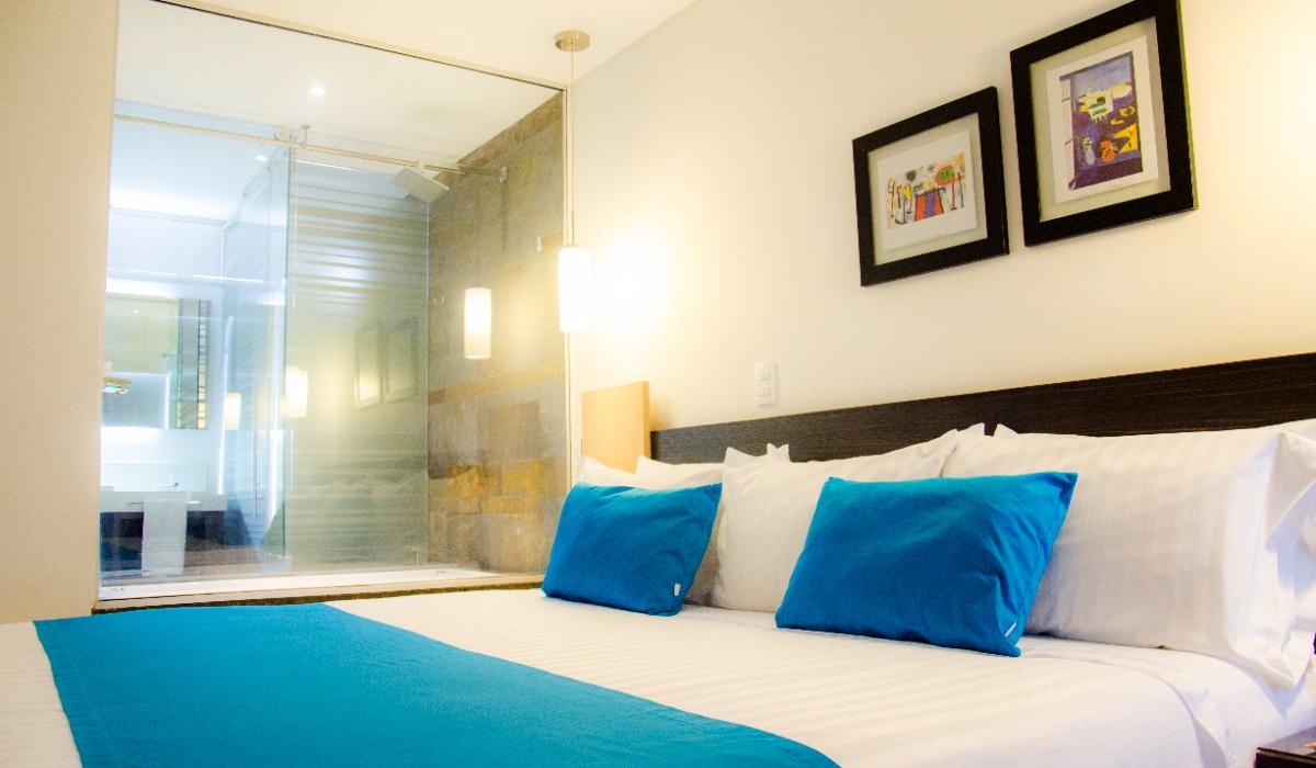 Habitación luminosa con cama king y decoración azul en Hotel Casablanca Cúcuta. Habitación luminosa con cama king y cojines azules en Hotel Casablanca Cúcuta.